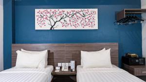 バンダ・アチェにあるAyani Hotel Banda Acehのベッドルーム1室(ベッド2台付)が備わります。壁には絵画が飾られています。