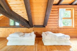 two white beds in a room with wooden walls at COTTAGE SaY in Nasushiobara