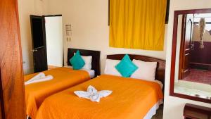 two beds in a room with orange sheets with flowers on them at Hospedaje Carliza II Backpackers in Puerto Ayora