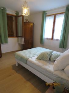 a bedroom with a bed with green curtains and a chandelier at l'altore di savaghju in Vivario
