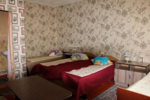 a bedroom with two beds and a wall with wallpaper at Guest House on Derbisheva in Karakol