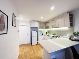 uma cozinha com armários brancos e um frigorífico branco em Stylish 2 Beds Apt SouthernCross with Pool & Gym em Melbourne