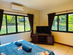 a bedroom with a bed and a flat screen tv at House of Garden Resort in Chiang Rai