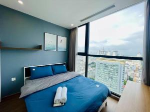 1 dormitorio con cama azul y ventana grande en VNRooms - 2BR Vinhomes Skylake near Shopping Mall, en Hanói