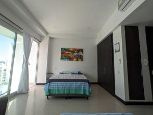a bedroom with a bed and a painting on the wall at Espectacular Apartamento-Loft, en el Rodadero. in Gaira