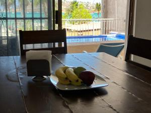 Vista al mar y alberca privada en Sector Bahía في سان كارلوس: صحن من الموز والتفاح على طاولة