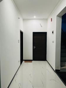 um corredor com uma porta preta e paredes brancas em Govardhan villas Guest House & Farm Stay em Bijāpur