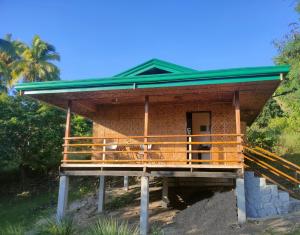 a house with a green roof and a porch at Marquis garden Eco-cottages in Tocdoc