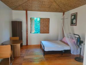 a bedroom with a bed and a table and a window at Marquis garden Eco-cottages in Tocdoc