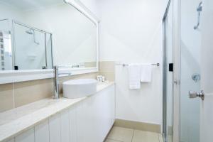 a white bathroom with a sink and a shower at The Marco Polo in Mackay