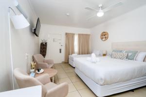 a white bedroom with a large bed and chairs at The Marco Polo in Mackay