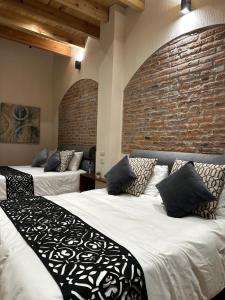- 2 lits dans une chambre avec un mur en briques dans l'établissement Hotel Del Valle, à Tecozautla