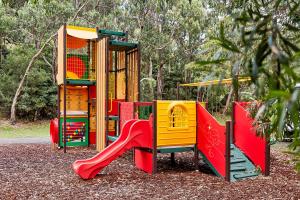 a playground with colorful play equipment in a park at Kennett River Family Caravan Park in Wye River