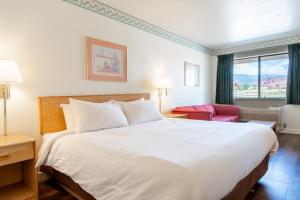 una habitación de hotel con una cama grande y una silla roja en Motel Torrey, en Torrey