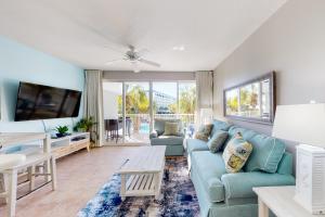 Una sala de estar con un sofá azul y una mesa. en Destin West Resort - Gulfside 207, en Fort Walton Beach
