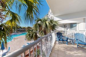 balcón con sillas azules y piscina en Destin West Resort - Gulfside 207, en Fort Walton Beach