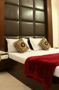 Hotel Maharaja Continental - New Delhi في نيودلهي: غرفة نوم مع سرير مع اللوح الأمامي من الجلد والوسائد