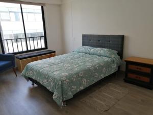 a bedroom with a bed with a green comforter and two windows at Cómodo y cálido departamento en San Isidro in Lima