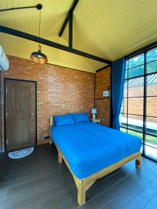 a bedroom with a blue bed in a brick wall at The Maewin Coffee & Cottage Economy Double Room in Ban Huai Rin
