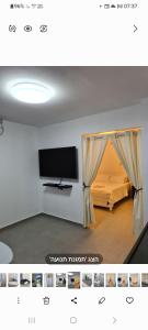 a room with a tv and a bed with a curtain at בוילה היפה של יהודית in Eilat