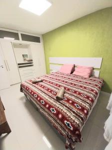 uma cama grande num quarto com paredes verdes em Flat Praia de Icaraí, 2 qts, 1vaga garagem e piscina em Niterói