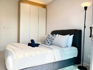 a bedroom with a white bed with a black headboard at Mercu Summer Suite Kuala Lumpur in Kuala Lumpur