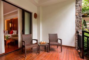 um alpendre com 2 cadeiras, uma mesa e um quarto em InterContinental Xishuangbanna Resort, an IHG Hotel em Jinghong