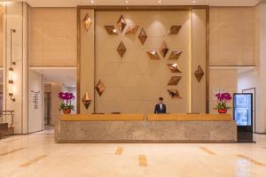 a man in a suit sitting at a reception desk in a lobby at Kare Hotel,Qianhai,Shenzhen in Shenzhen