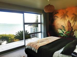 a bedroom with a large window with a view of the ocean at Once Upon a Tide in Auckland
