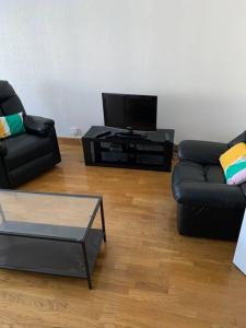 a living room with two black couches and a tv at Reims centre-ville pour 6 personnes in Reims