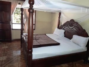 a bedroom with a wooden bed with a canopy at Sydney Hotel Kampala in Kampala