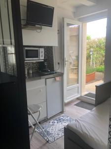 a small kitchen with a microwave and a door to a patio at STUDIO 11m2 in Magny-Cours