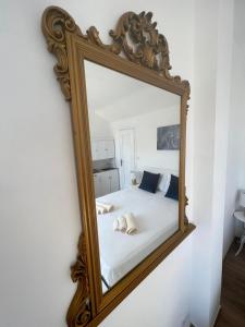 a mirror hanging on a wall next to a bed at Fior di Loto Suite - Lingotto in Turin