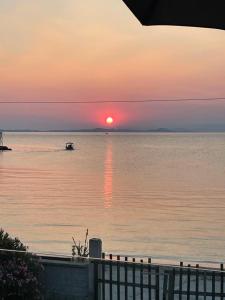 a sunset over a body of water with a boat at Seafront Apartment in Skala Mistegnon