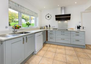 a kitchen with white cabinets and a sink at Sunnydale in Llanbedrog