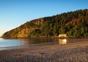 a house on a beach next to the water at Sunnydale in Llanbedrog