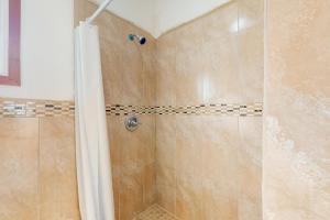 uma casa de banho com um chuveiro e uma porta de vidro em Hummingbird Estate em Dangriga