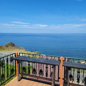 a bench sitting on a balcony looking at the ocean at taiza house in Kyotango