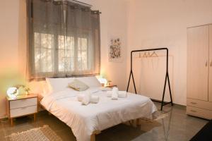um quarto com uma cama com lençóis brancos e uma janela em Charming 2 BR in the Heart of Haifa by Sea N Rent em Haifa