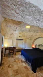 - une chambre avec un lit et une table dans un mur en pierre dans l'établissement Vacanza In Puglia, à Alberobello