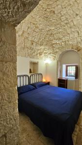 - une chambre avec un lit bleu dans un mur en pierre dans l'établissement Vacanza In Puglia, à Alberobello