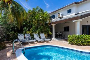 - une piscine avec 2 chaises et une maison dans l'établissement Koyari 36-F, à Palm-Eagle Beach