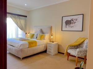 a bedroom with a bed and a chair and a window at Covesto Guesthouse - Waterkloof in Pretoria