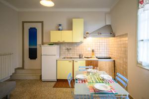 a kitchen with a table and a white refrigerator at Casa stella in San Lorenzo al Mare
