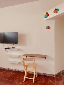 Habitación con silla de madera y TV en la pared. en Casa Alcalde Alojamiento centro Guadalajara en Guadalajara