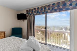 a bedroom with a bed and a large window at Bayview East & West in Holden Beach
