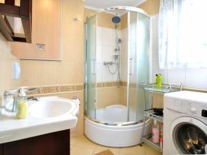 a bathroom with a shower and a sink and a washing machine at domek PERKUN in Pierkunowo +4 photos