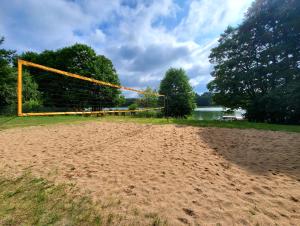 a volleyball net on a sandy beach next to a lake at Villa nad Kalwą in Tylkowo