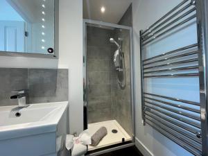 uma casa de banho com um chuveiro e um lavatório. em Stunning Town Centre Penthouse w/ Sea Views em Penzance