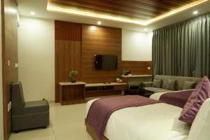 una camera d'albergo con due letti e una televisione di VOVO PREMIER HOTEL a Bangalore